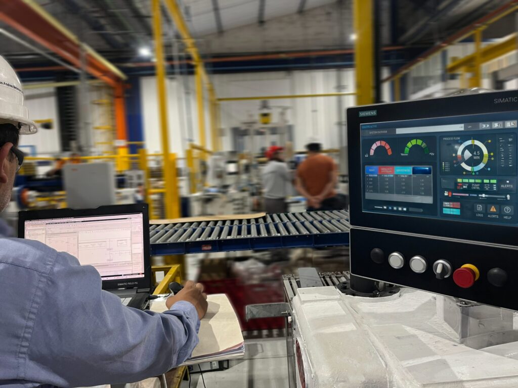 Ingeniero de TDMEK realizando programación de PLC y monitoreo de procesos industriales mediante pantalla HMI Siemens SIMATIC en planta.